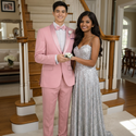 Two people in formal attire standing in a home setting taking a photo before prom.